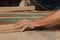 Hands of worker shaving a piece of wood on router table in carpentry workshop.