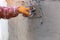 The hands of a worker who are plastering up close are wearing orange rubber gloves to prevent the cement from biting their hands,