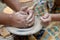 Hands working on a piece of clay of a rotating pottery wheel