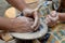 Hands working on a piece of clay of a rotating pottery wheel