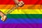 Hands wrapped in heavy iron chains against the background of the LGBT rainbow flag, Pride flag, Freedom flag - an international