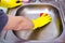 Hands in yellow gloves clean sink with sponge and a special cleaning agent, detergent spray. Hygiene in the kitchen, cleaning the