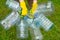 Hands in yellow gloves holding big empty plastic bottles. Grass on a background