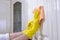 Hands in yellow rubber protective gloves wipe the furniture from dust. House cleaning service, side view, close-up