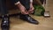 Hands of young Asian groom tying shoelaces on stylish black leather shoes. Unrecognizable happy young man getting ready