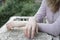 Hands of a young blonde with pink manicure lie on an old cracked concrete column.