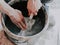 Hands of a young caucasian man washing a dirty spatula from putty in a black bucket