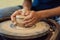 Hands of young craftsperson holding by rotating pottery wheel