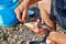 The hands of a young fisherman remove the caught fish from the hook against the blurred background of the pebble beach