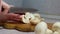 Hands of young girl cut a mushroom on the wooden cutting board, light background, close up