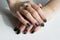 hands of a young girl with green manicure, which shows a sign of biological danger biohazard. On one finger - a gold ring with an