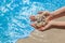 The hands of a young girl hold a pile of shells against the background of the blue sea on the beach close-up