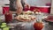 Hands of young girl sprinkles cheese pizza dough