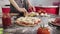 Hands of young girl sprinkles cheese pizza dough