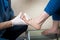 The hands of a young man doctor orthopedist conducts diagnostics, foot foot test of a woman, for the manufacture of individual, or