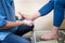 The hands of a young man doctor orthopedist conducts diagnostics, foot foot test of a woman, for the manufacture of individual, or