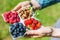 The hands of a young man hold a white plate with a mixture of fresh berries