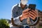 Hands of young man with mask with mobile phone and fixed gear bicycle in the street in time of coronavirus. Selective focus on