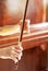 Hands of a young violinist rosin his bow on the background of a piano illuminated by the sun, vertical