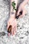 Hands of a young woman with a bottle of serum and a pipette on a marble background.