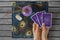 Hands of young woman with golden nail polish holding three tarot or oracle cards, on a black peacock feathers pattern