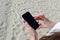 Hands of young woman holding cellphone on beach. Remote work concept, freelance. Copy space for text