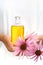 Hands of young woman holding essential oil and fresh coneflowers