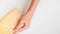 Hands of young woman runs over large piece of hard cheese in package on white background top view. Fresh tasty cheese