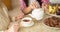 Hands of young woman with white china teapot pouring tea into cup of her senior mother