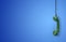 The handset of an old analog telephone hangs on a wire on a blue background