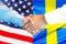 Handshake on american and Swedish flag background