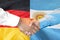 Handshake on Argentina and Germany flag background