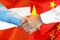 Handshake on Austria and China flag background