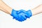 Handshake with blue medical gloves.