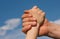 Handshake of a child and an adult against a blue sky