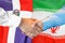 Handshake on Dominican Republic and Iran flag background. Support concept