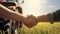 handshake of farmers in shirts against the background of a wheat field with a tractor