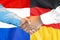 Handshake on Germany and Netherlands flag background