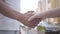 Handshake of middle eastern man and caucasian woman in front of city background close-up. Love, friendship, the romantic