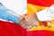 Handshake on Spain and Poland flag background