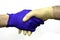 Handshake of two hands in protective hygienic surgical gloves of different colors on the white background