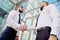 Handshake of two young men against a multi-storey office building. Make a deal. Friendly relations. Office staff. Signing