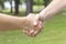 Handshake of two young people in the summer in the park on a background of green grass