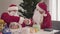 Handshake of young and senior Santas on Christmas eve. Portrait of two confident men in Santa Clause costumes sitting at