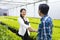 Handshaking between Asian farmer and his new local business entrepreneur inside his hydroponics salad lettuce greenhouse for new