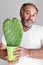 Handsom bearded mature man holds a heart-shaped cactus in the pot. Portrait with funny romantic facial expression.