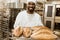 handsome african american baker with tray of fresh loaves of bread