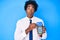 Handsome african american business man with afro hair holding dataphone and credit card making fish face with mouth and squinting