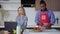 Handsome African American husband in apron cutting salad in kitchen as busy Caucasian woman messaging online on laptop