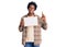 Handsome african american man with afro hair holding blank empty banner surprised with an idea or question pointing finger with